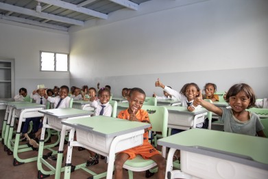 Nieuwe schoolmeubels voor de kinderen, ze kijken lachend naar de camera.