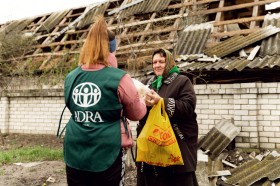 Een ADRA-medewerker overhandigt een noodhulppakket aan een Oekraïense vrouw.